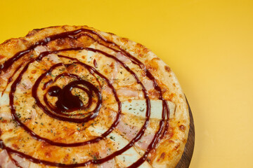 rustic bbq pizza with chicken and ham on wooden board and yellow background