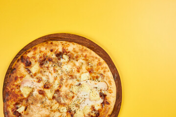 rustic pineapple and chicken pizza on wooden board and yellow background