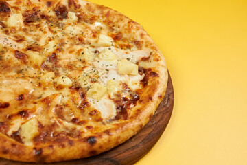 rustic pineapple and chicken pizza on wooden board and yellow background