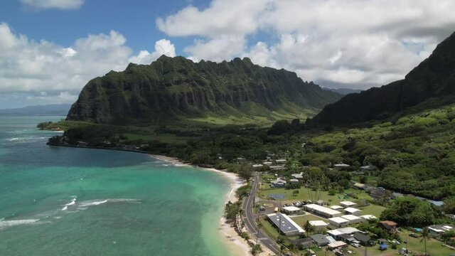 Drone hyperlapse of small Hawaii coastal village and green mountains. Aerial 4K timelapse filmed near Kualoa Ranch and Kaaawa on the east coast of Oahu. 