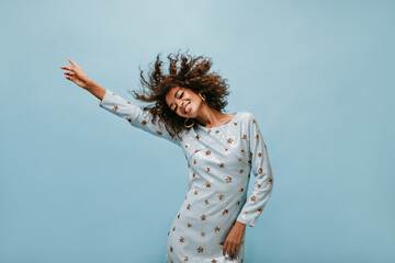 Wonderful woman with wavy hair in round cool earrings and long sleeve stylish dress smiling and...