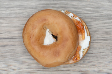 Overhead view of cream cheese and jelly bagel cut in half and ready to eat for breakfast