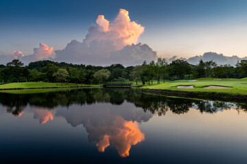 ゴルフ場の夕焼けに染まる水鏡の入道雲