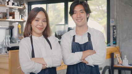 Portrait of happy handsome young man and beautiful woman confident cafe owner standing crossed arms on front counter bar together at the cafe coffee shop, Owner small business concept