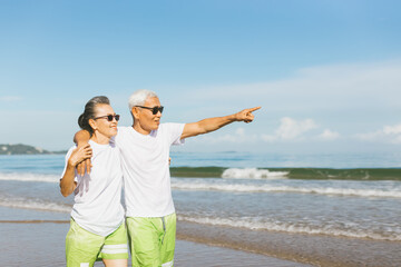 Romantic Senior couple strolling happily along the beach in the sunshine and bright sky. Plan life...