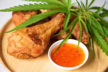 Cannabis food nature herb concept, Fried chicken leg on plate with chicken dipping sauce, crispy fried chicken food with cannabis leaf - marijuana leaves plant