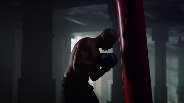 Man doing boxing training in fighting club. Boxer fighting with punching bag