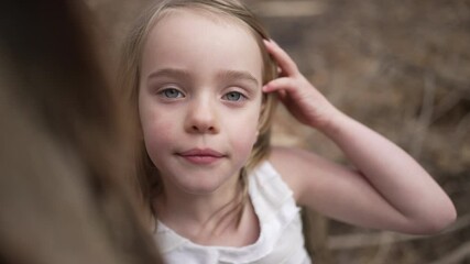 Slow motion portrait of a little girl brushing hair out of her face.