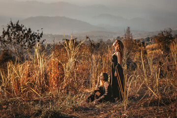 two beautiful young stylish woman at the field at sunset