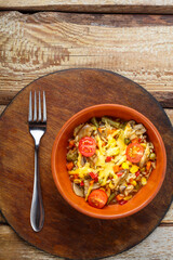 Risotto with mushrooms in a clay plate on a wooden background on a round board near a fork.