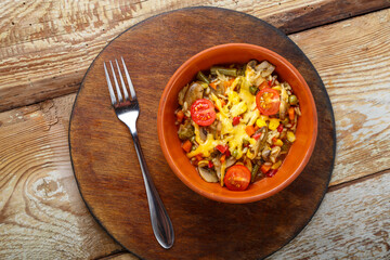 Risotto with mushrooms in a plate on a wooden background on a wooden round stand next to a fork.