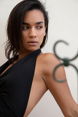 attractive latin young woman with short black hair, wears a black blouse, is posing in studio,...