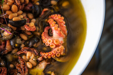 octupus and olives in olive oil inside a white bowl
