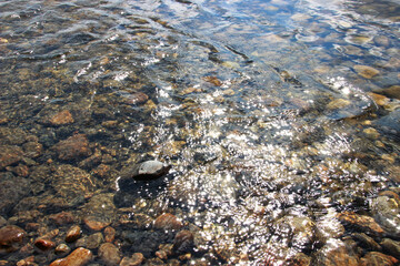 brown and gray stones in the water with the reflected sun