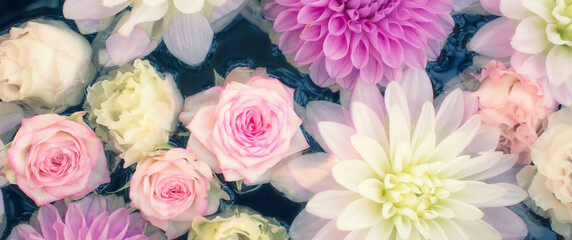White and pink flowers floating on water. Dahlias, roses, lisianthus.