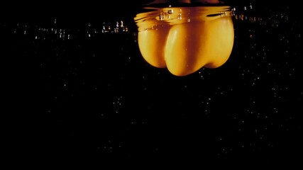Yellow pepper paprika falling into water with bubbles on black background - Powered by Adobe