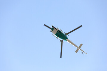 Fototapeta premium Helicopter with video surveillance system flying in blue sky. Takes video from sports competitions