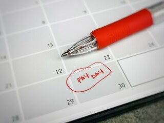 Close up text pay day written on calendar with a pen. Reminder concept of payment. Selective focus.