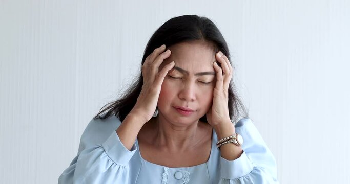 A senior Asian woman suffered and pain from headaches using hand holding head. Concept of older person health care.