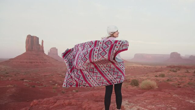Woman with traditional pattern blanket in red west American desert at sunset 4K