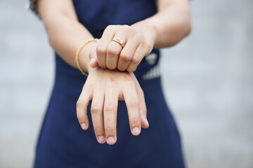 Woman scratching arm from itching on light gray background. Cause of itchy skin include insect...