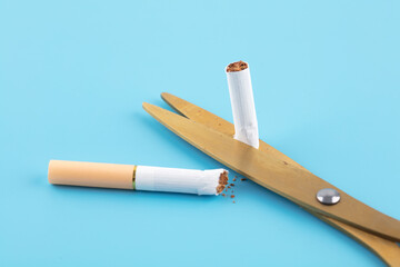 A cigarette cut by scissors on a blue background