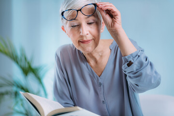 Senior Woman With Eyeglasses Having Problems with Book Reading. Indication for Cataract, Glaucoma, and Vision Loss in the Elderly.