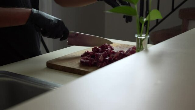 Chef is dicing the most delicious fresh chuck of beef, using black gloves and sharp chef knife. (close up shot)