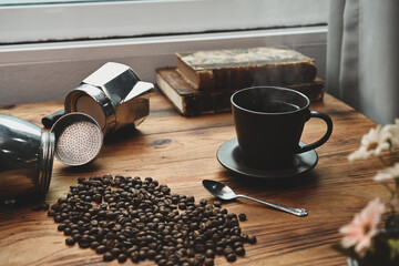 Roasted coffee beans, coffee cup and coffee maker moka pot on wooden table.