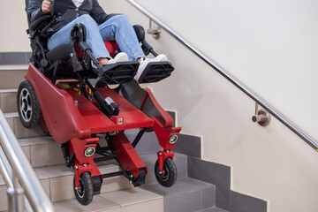 Caucasian woman in wheelchair with electric caterpillar going down stairs.