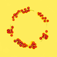 Creative circle made of fresh organic red currant on yellow background. Flat lay arrangement.