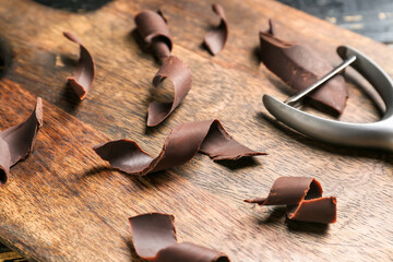 Board with chocolate curls and cutter, closeup