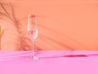 A glass of champagne with red currant posh concept arrangement against terracotta and light purple...