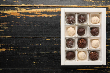 Box with sweet chocolate candies on dark wooden background