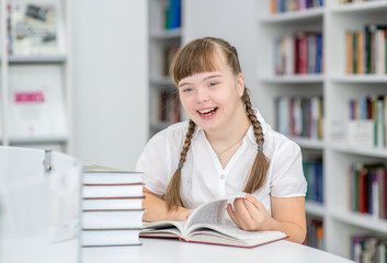 Happy girl with syndrome down at library.  Education for disabled children concept