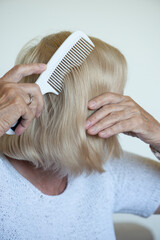 A senior woman combing her hair. Close up.