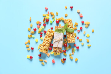 Healthy cereal bars and candied fruits on color background