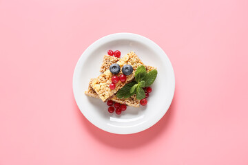 Plate with healthy cereal bars and berries on color background