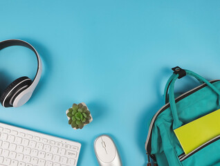 flat lay of headphones, computer keyboard, mouse, school backpack and cactus  on blue background with copy space. Online learning concept.