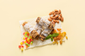 Healthy cereal bars, raisins and nuts on color background