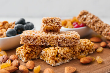 Board with healthy cereal bars, berries and nuts on light background