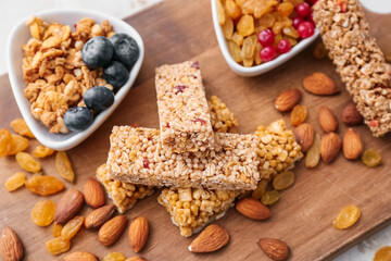 Fototapeta na wymiar Board with healthy cereal bars, berries and nuts on light background