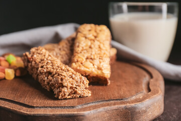 Board with healthy cereal bars, candied fruits and nuts on dark background