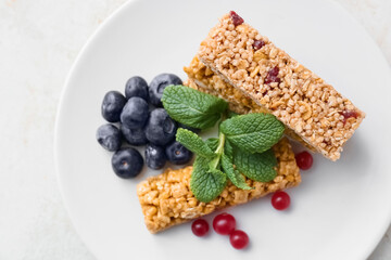 Plate with healthy cereal bars and berries on light background