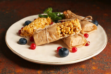 Plate with healthy cereal bars and berries on grunge background