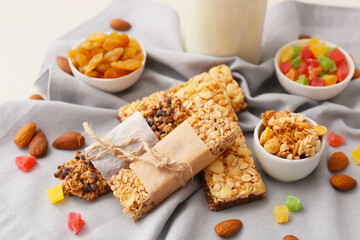 Healthy cereal bars, candied fruits and nuts on light background