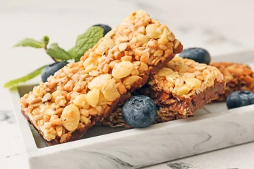 Foto op Plexiglas Plate with healthy cereal bars and berries on light background © Pixel-Shot