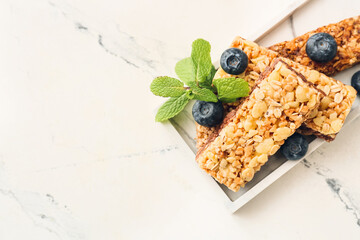 Plate with healthy cereal bars and berries on light background