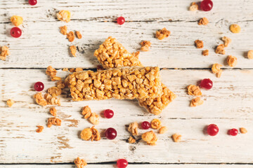 Healthy cereal bars and cranberries on light wooden background