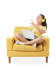 Young woman with laptop listening to music while sitting in armchair on white background